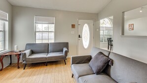 A living room with two grey sofas, a wooden coffee table, and a door with a decorative glass panel. - Explore Gulfport Beaches: Family Home w/ Yard (Gulfport)