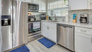 Une cuisine moderne avec des appareils en acier inoxydable, des meubles blancs et un tapis bleu.