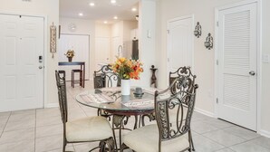 Uma sala de jantar com uma mesa redonda, cadeiras e um vaso de flores.