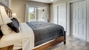 A bedroom with a bed, a nightstand, a lamp, and a view of the outside. - Resort Perks & Family Fun! St George Retreat (St. George)