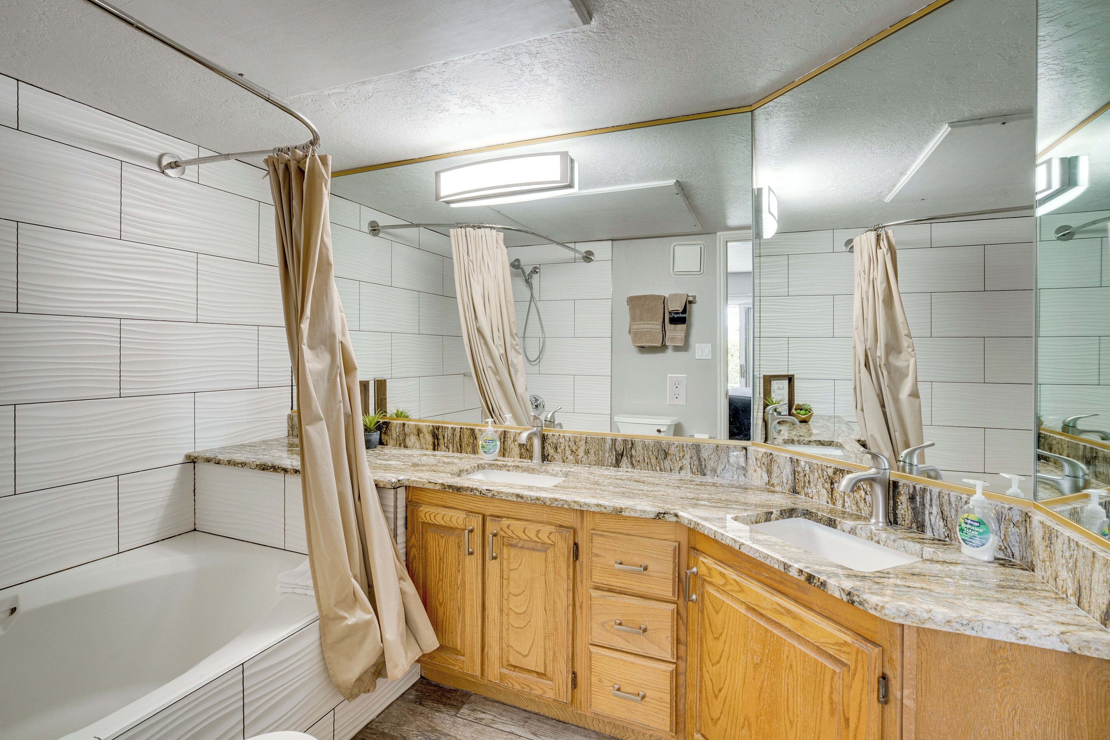 A modern bathroom with a bathtub, a sink, and a vanity with a mirror.