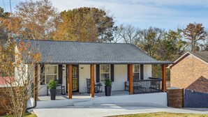 Een tweelaags huis met een overdekte veranda, een bakstenen gevel en een voortuin.