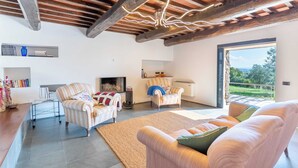 A spacious living room with a fireplace, striped armchairs, a sofa, and a view of the outdoors. - Pieve Vecchia - Charming and modern villa in Tuscany (Toscana)