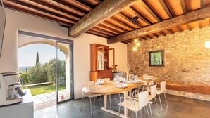 A dining area with a stone wall, wooden ceiling beams, and a view of the outdoors. - Pieve Vecchia - Charming and modern villa in Tuscany (Toscana)