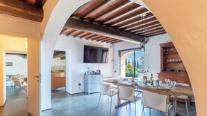 A spacious dining area with a wooden table and chairs, a kitchen in the background, and a TV mounted on the wall. - Pieve Vecchia - Charming and modern villa in Tuscany (Toscana)