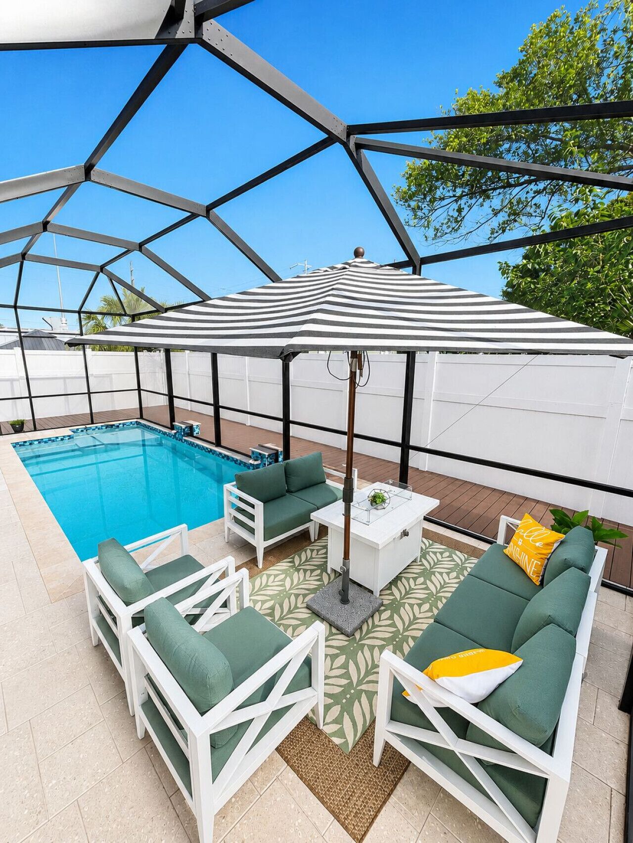 A poolside area with a covered seating area, a pool, and a view of the sky.