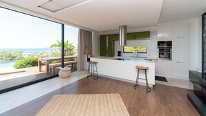 Una cocina moderna con una isla grande, taburetes de bar y vistas al océano.