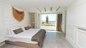 Un dormitorio con una cama grande, vistas a la ciudad y un balcón con vistas al mar.