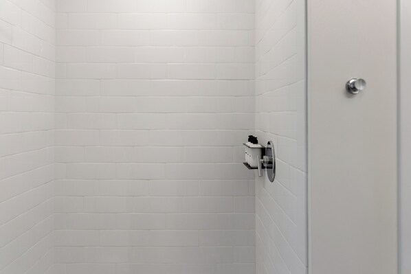 A bathroom with white tiled walls and a door with a silver handle. - Hyatus Luxury Residences Everett (Everett)