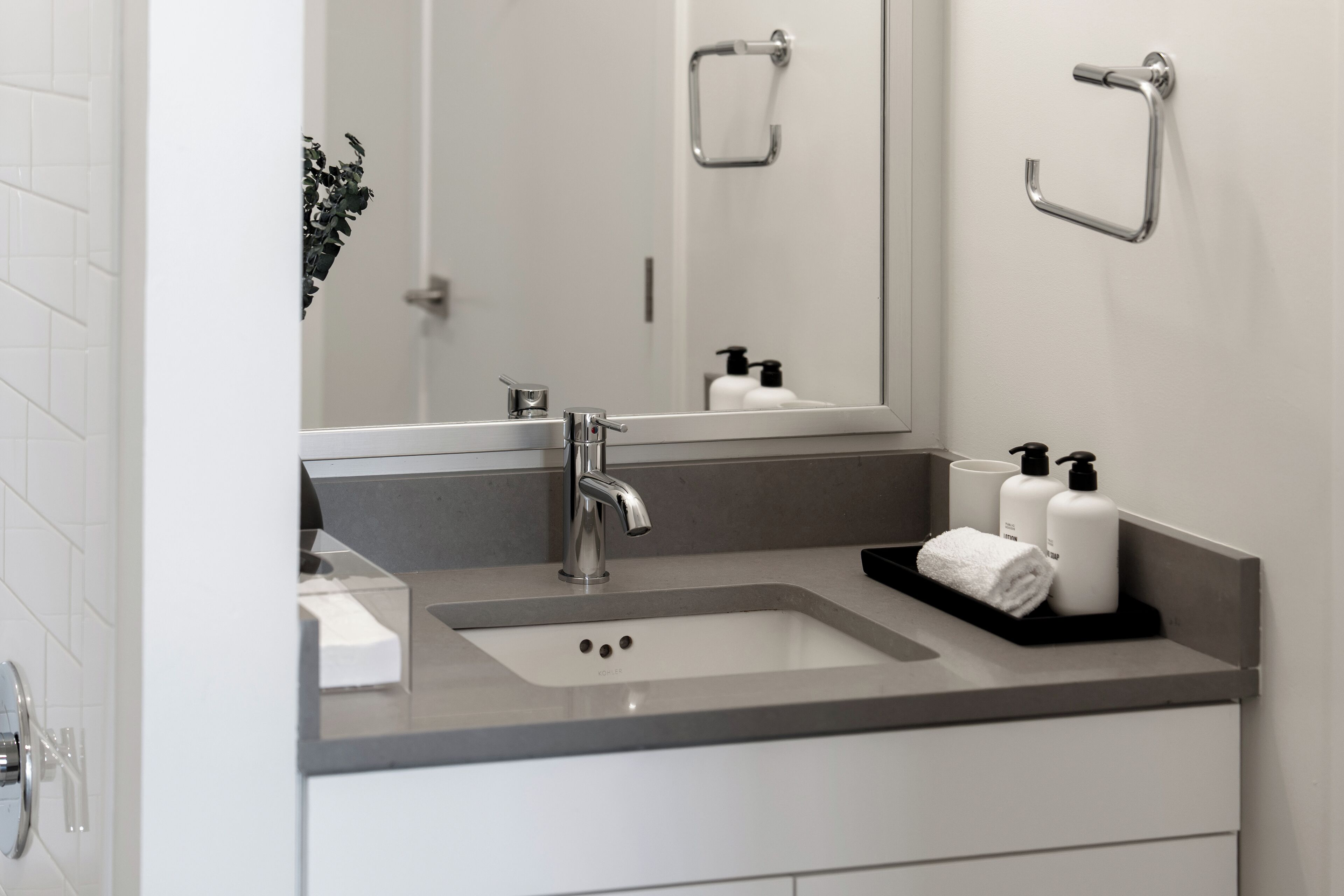 A modern bathroom with a white sink, a mirror, and a towel rack.