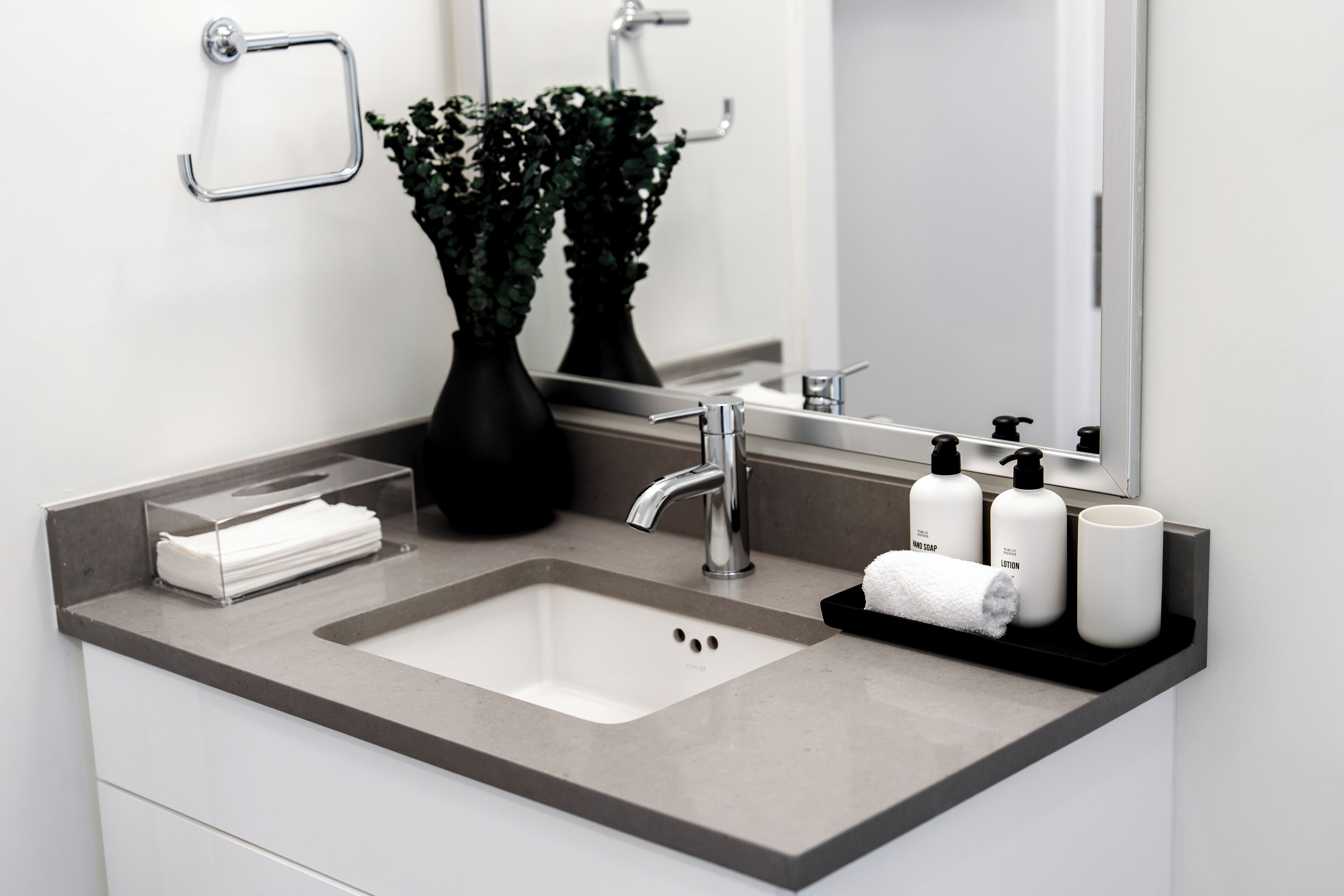 Ein modernes Badezimmer mit einem rechteckigen Waschbecken, einem Spiegel und einem Ablagebereich für Toilettenartikel.