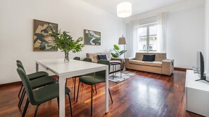 A modern living room with a dining area, featuring a white table, green chairs, a beige sofa, and two abstract paintings on the wall. - Easylife - Milan - italia 11 P4 - Historic Center (Milano)