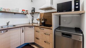 A modern kitchen with a built-in dishwasher, a microwave, and a stove. - Charming apartment with pool, near center and lake, sleeps 4 (Sanguinet)
