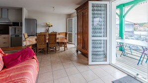A compact living space with a kitchenette, dining area, and a large sliding glass door leading to an outdoor deck. - Charming apartment with pool, near center and lake, sleeps 4 (Sanguinet)