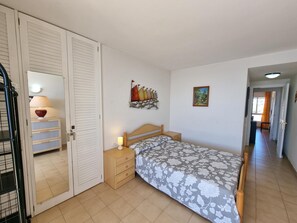 A bedroom with a bed, a nightstand, a lamp, a wardrobe, and a painting on the wall. - Modern apartment near beach with terrace (L'Escala)