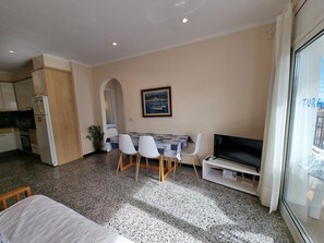 Uma sala de estar moderna com área de jantar, televisão e cozinha.
