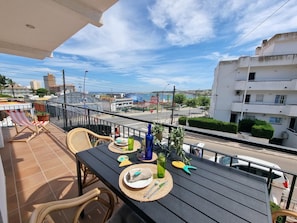 Uma varanda com mesa posta para refeições, cadeiras e vista para a cidade.