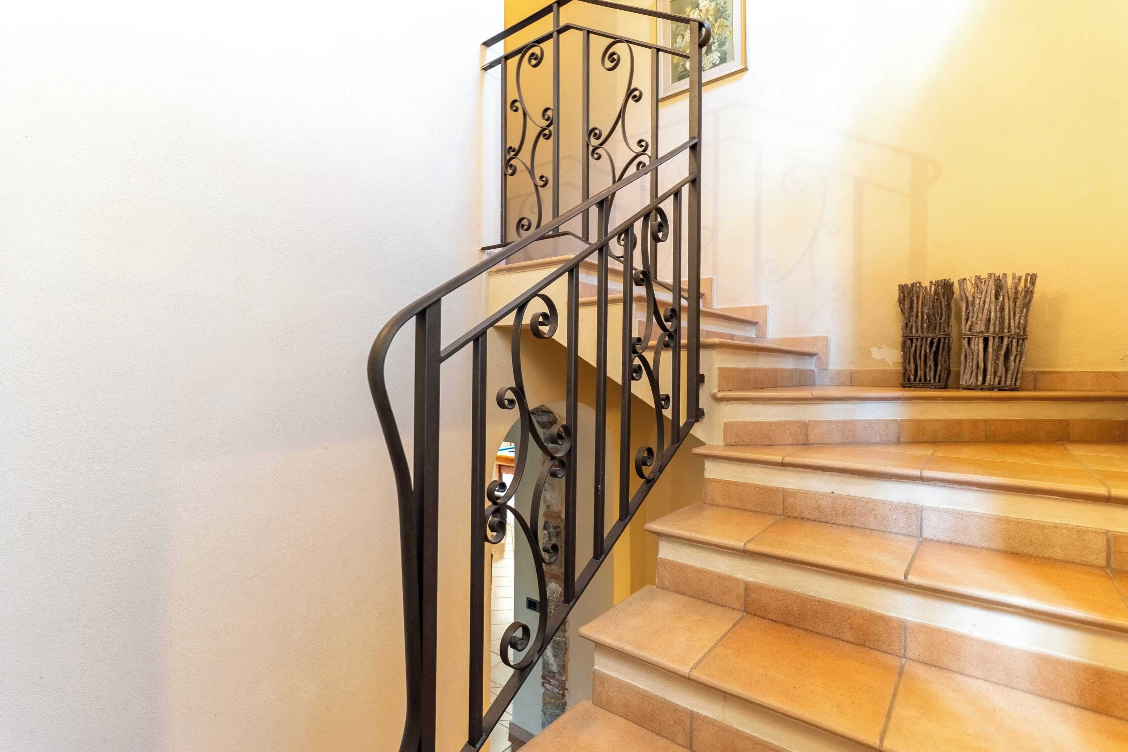 A staircase with ornate black railings and beige steps.