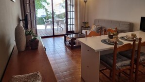 A cozy living area with a sofa, dining table, and chairs. There is a sliding glass door leading to an outdoor patio with a table and chairs. - Cozy apartment with terrace 400m from the beach (L'Escala)