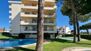 A multi-story building with balconies, a swimming pool, and a well-maintained lawn. - Cozy apartment with terrace 400m from the beach (L'Escala)
