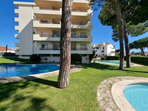 A multi-story building with balconies, a swimming pool, and a well-maintained lawn. - Cozy apartment with terrace 400m from the beach (L'Escala)