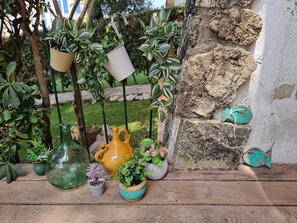 A variety of potted plants and decorative items on a wooden surface, with a stone wall and a metal fence in the background. - Cozy apartment with terrace 400m from the beach (L'Escala)