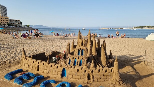 Ein Strand mit einer großen Sandburg mit der Aufschrift "LEGALE".