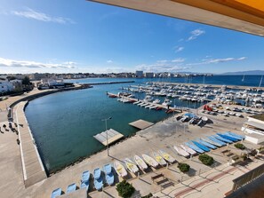 Ein Yachthafen mit vertäuten Booten, einer gewundenen Uferlinie und Blick auf die Stadt im Hintergrund.
