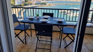 Een balkon met een tafel voor vier personen, met uitzicht op een jachthaven met boten en gebouwen op de achtergrond.