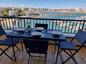 A balcony table with chairs, a view of a marina, and buildings in the background. - Apartment with private terrace in L'Escala, near the beach (L'Escala)
