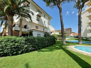 Un hôtel à plusieurs étages doté de balcons, d’une piscine et d’espaces verts bien entretenus.