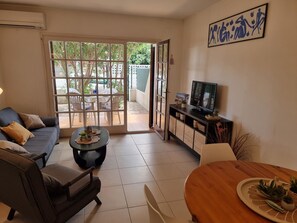 Ein Wohnzimmer mit einer Couch, einem Couchtisch, einem TV-Schrank und einem Essbereich mit Tisch und Stühlen.