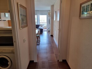 A hallway with a washing machine, a dining area with a table and chairs, and a sofa. - Cozy apartment near the beach with air conditioning (L'Escala)