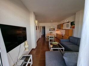 A living room with a TV, sofa, and a dining area with a table and chairs. - Cozy apartment near the beach with air conditioning (L'Escala)