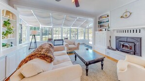 A spacious living room with a fireplace, a ceiling fan, and large windows. - A rambling farmhouse, now a modern and comfortable sanctuary for you to enjoy! (Harpswell)