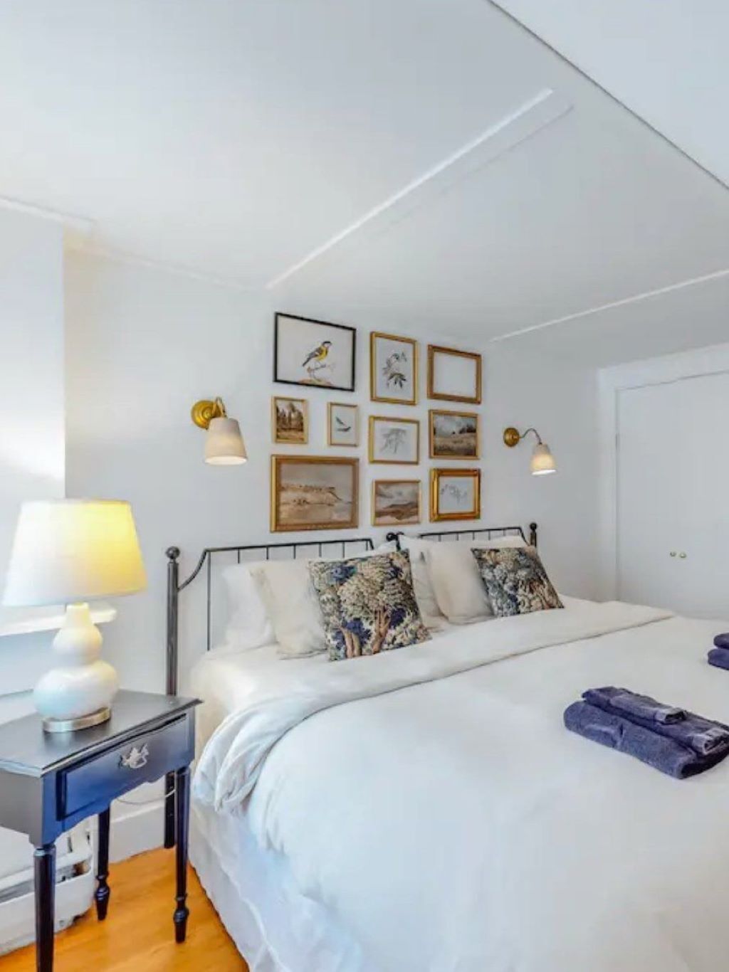 A neatly arranged bedroom with a bed, bedside tables, and wall-mounted lamps.
