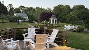 A wooden deck with Adirondack chairs and a gazebo in the background. - A rambling farmhouse, now a modern and comfortable sanctuary for you to enjoy! (Harpswell)
