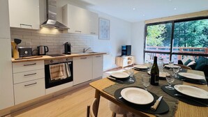 A modern kitchen with white cabinets, a wooden countertop, and a dining area with a table set for two. - Renovated apartment for 6 near slopes - Les 2 Alpes (Les Deux Alpes)