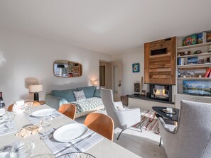 A modern living room with a fireplace, a dining area with a table set for four, and a cozy seating area with a sofa and armchairs. - Spacious apartment with parking and pets allowed, near Chamonix (Chamonix-Mont-Blanc)