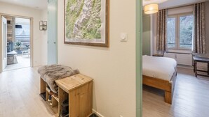 Un dormitorio con cama, un banco de madera, un mapa en la pared y vistas al exterior a través de una ventana.