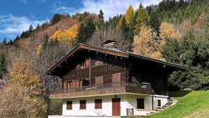 Eine Holzhütte mit Balkon, gelegen an einem Hügel inmitten von Herbstlaub.