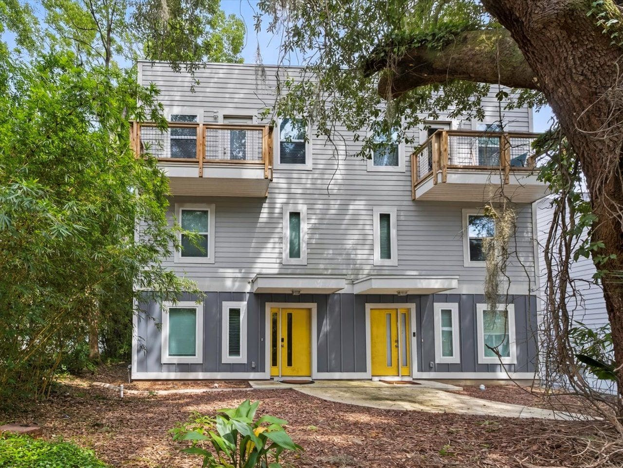 A two-story residential building with a balcony on the upper floor, a front door, and a small porch area.