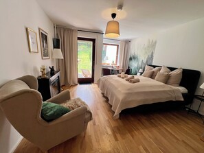 A bedroom with a bed, a chair, a desk, and a view of the outdoors. - Black Forest Hideaway🌲 (Schönwald im Schwarzwald)
