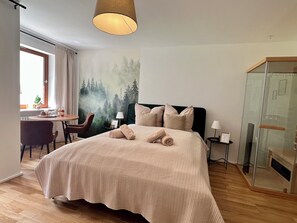A hotel room with a bed, a desk with a chair, a window with curtains, and a forest mural on the wall. - Black Forest Hideaway🌲 (Schönwald im Schwarzwald)