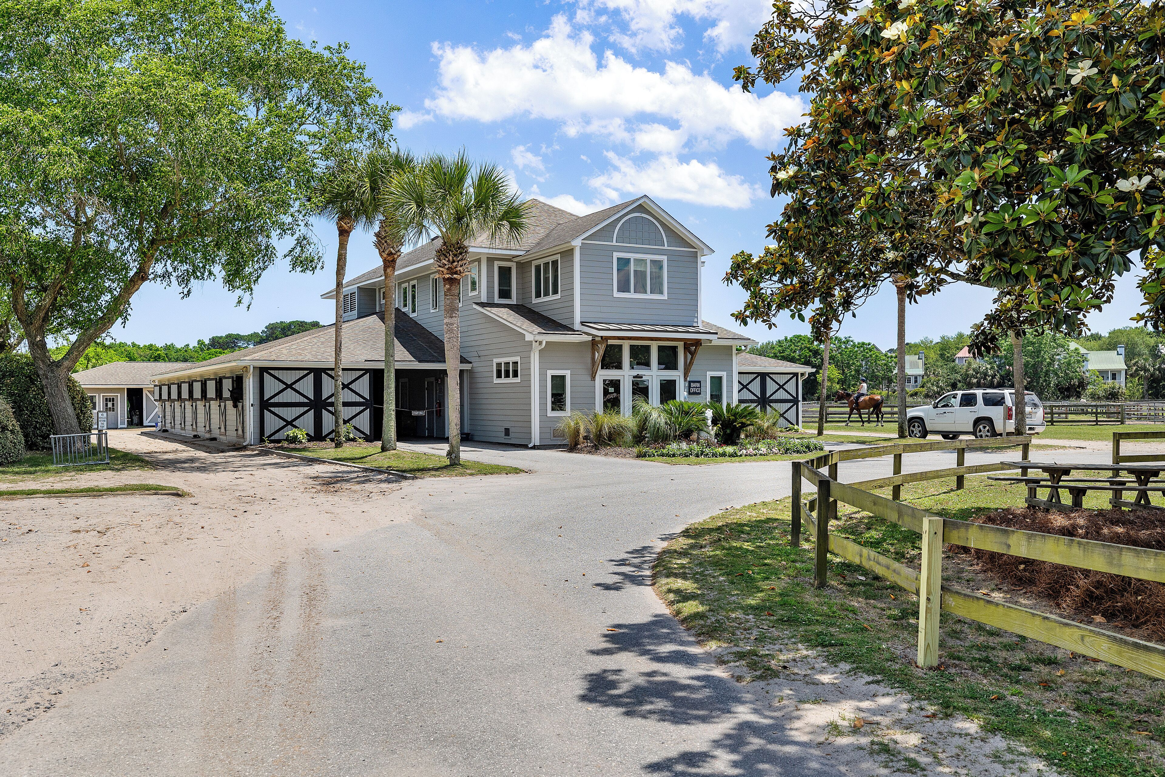 A two-story building with a garage, a covered driveway, and a picnic area with benches.