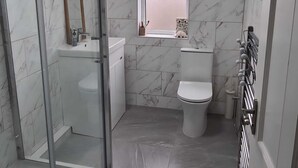 Een moderne badkamer met een douchecabine van glas, een toilet en een bidet.