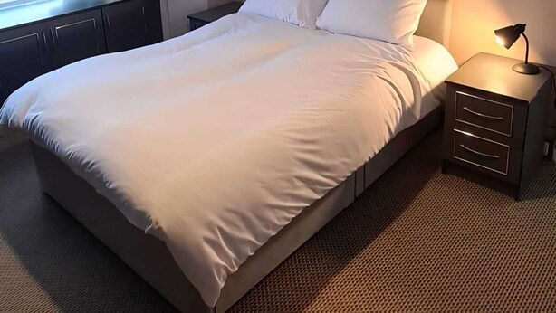 Een keurig opgemaakt bed met witte lakens in een hotelkamer.