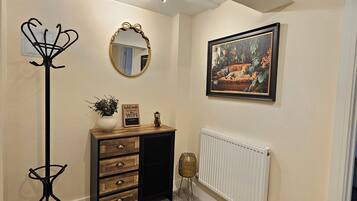 Une pièce comprenant une commode en bois, un miroir, un radiateur et un tableau encadré accroché au mur.
