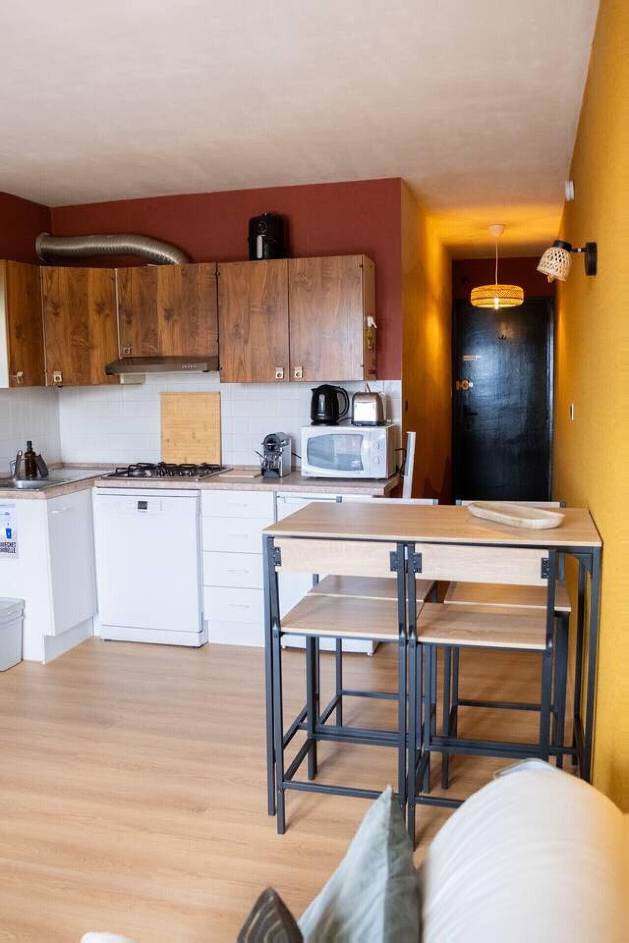 Eine kleine Küche mit Holzausstattung, einer Mikrowelle, einem Wasserkocher und einem kleinen Kühlschrank.
