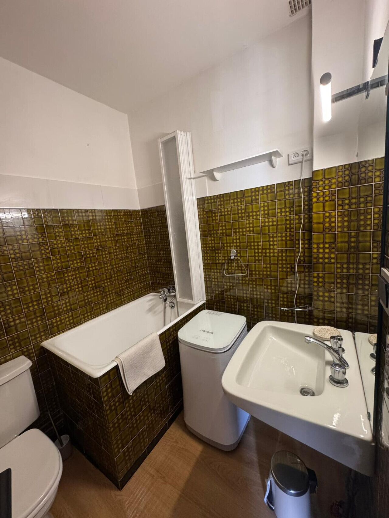 A bathroom with a bathtub, toilet, sink, and a trash bin.